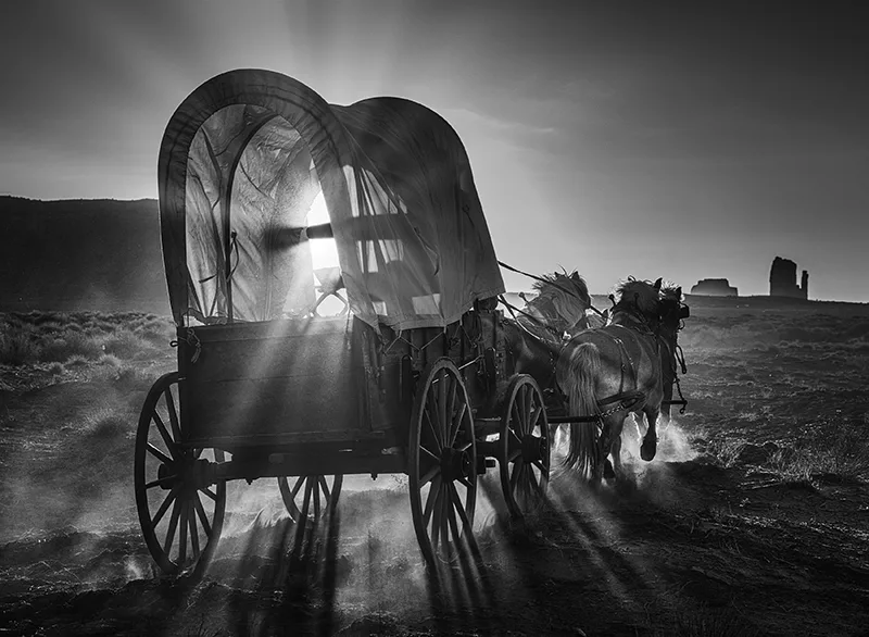 Photo of horse pulled wagon moving across the prairie by David Yarrow.